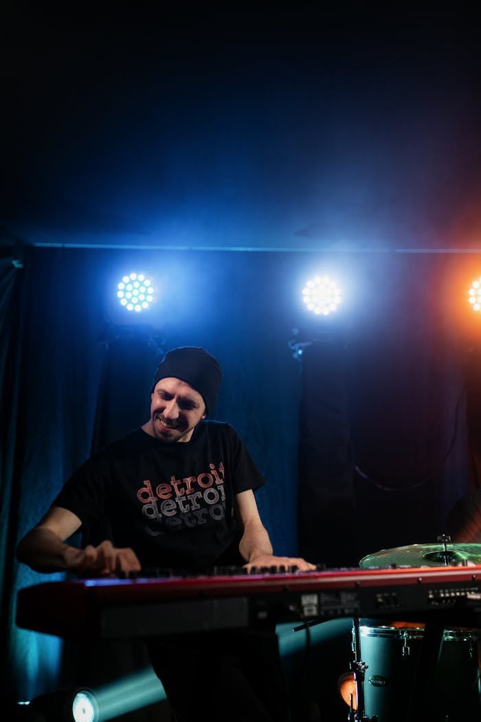 Musician passionately plays keyboard under colorful stage lights.
